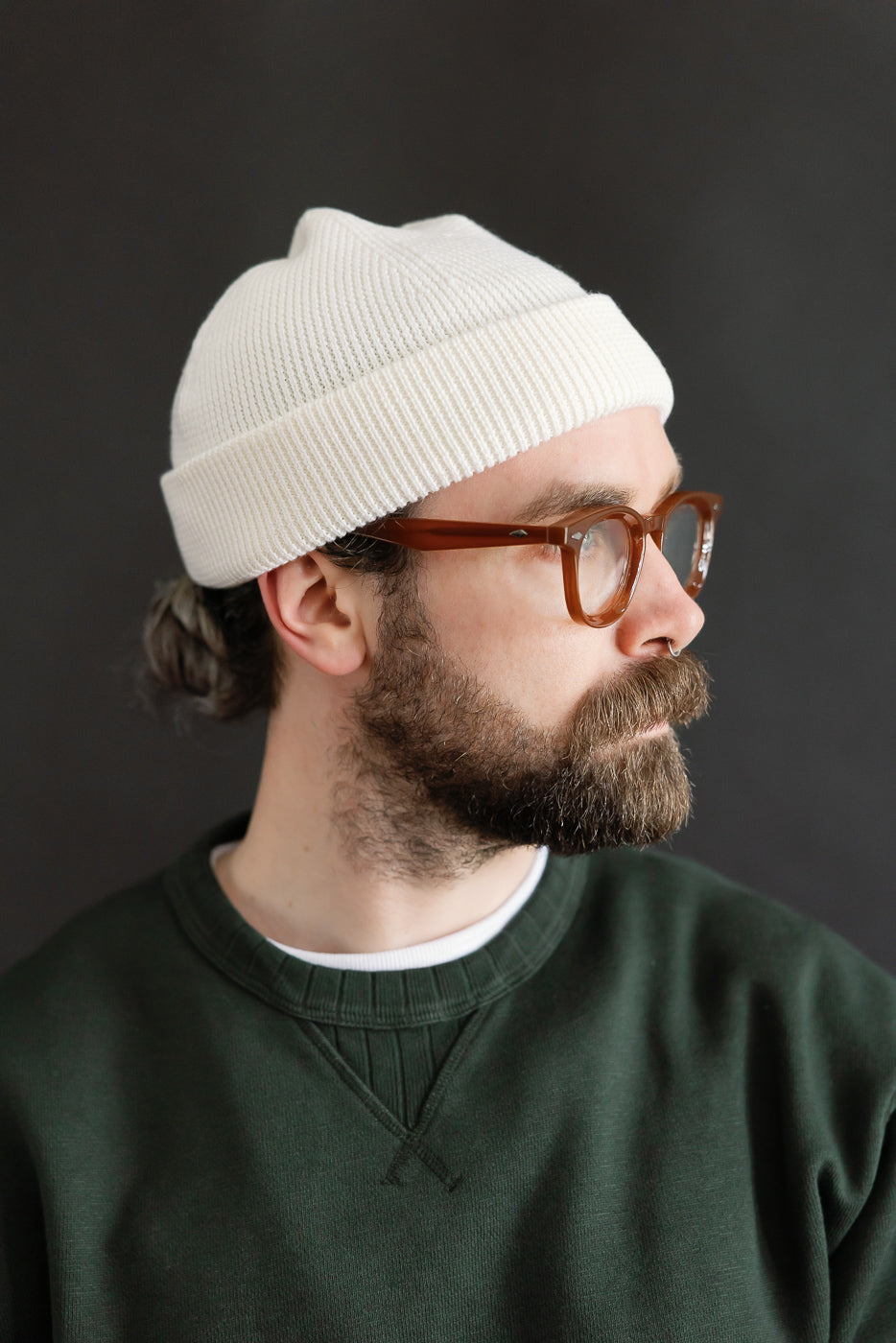 Close-up side view of Merz B. Schwanen ribbed merino wool watch cap in natural on male model, 5'9