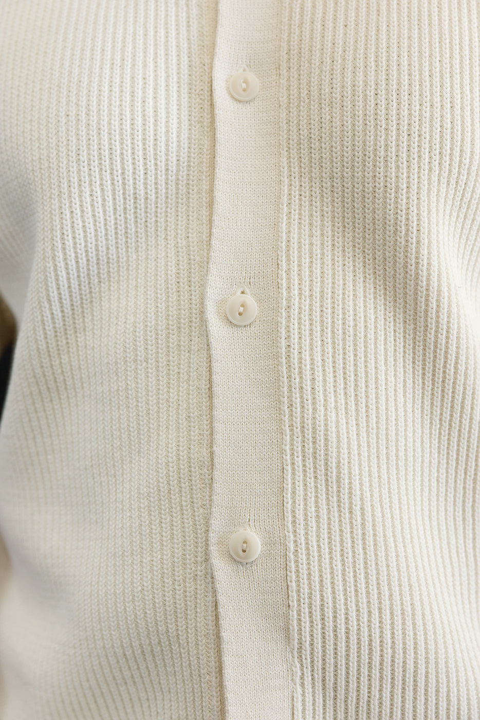 Close-up of front ribbed cotton knit short sleeve shirt, highlighting buttons and texture.