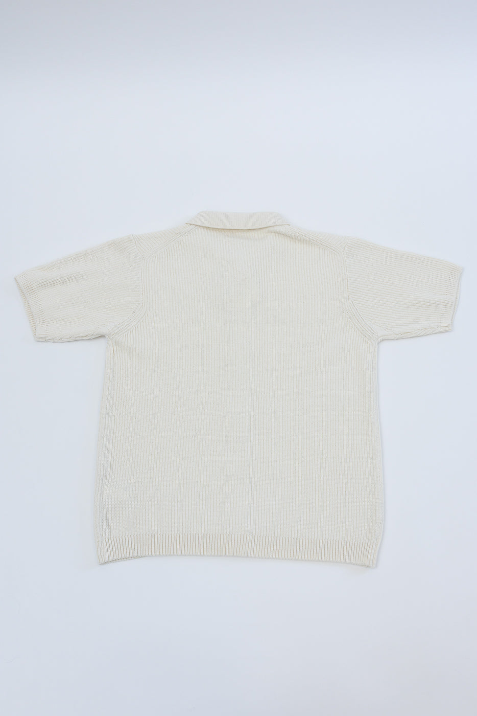 Flat lay of ribbed cotton knit short sleeve shirt in natural color, showing full back view.