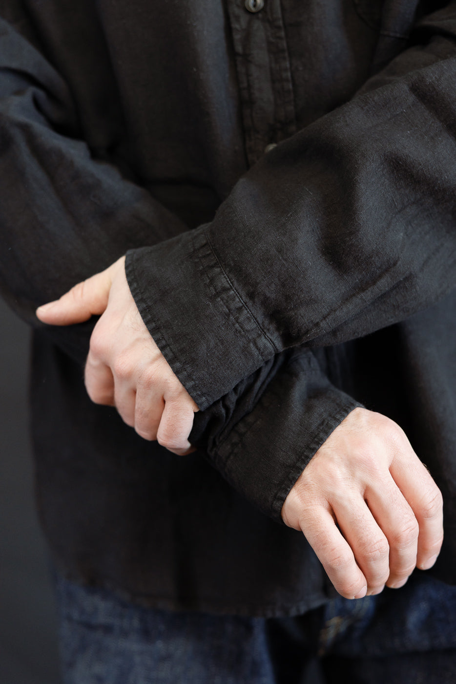 Person adjusting sleeve cuff of SHIRT20LI.99 - Organic Linen Long Sleeve Shirt - Black, showcasing the garment-dyed organic linen's texture and casual fit, highlighting its effortless style for warm weather.