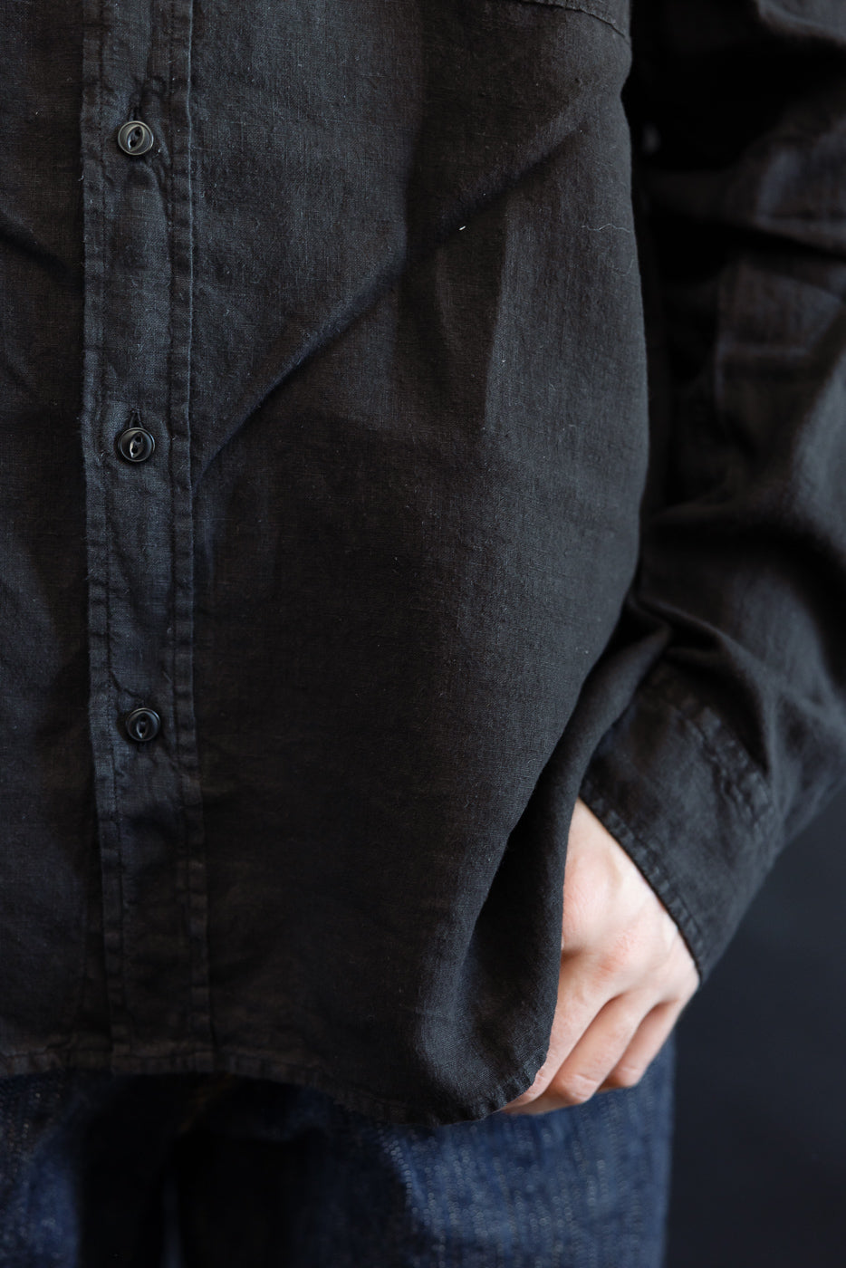 Close-up of the SHIRT20LI.99 - Organic Linen Long Sleeve Shirt - Black, showcasing its airy, regular fit with visible Corozo nut buttons and soft draping over denim.