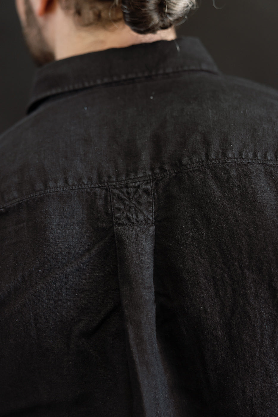 Rear view of the SHIRT20LI.99 - Organic Linen Long Sleeve Shirt - Black, showcasing the yoke seam, box pleat, and collar, highlighting the garment's airy, cropped fit and premium craftsmanship.