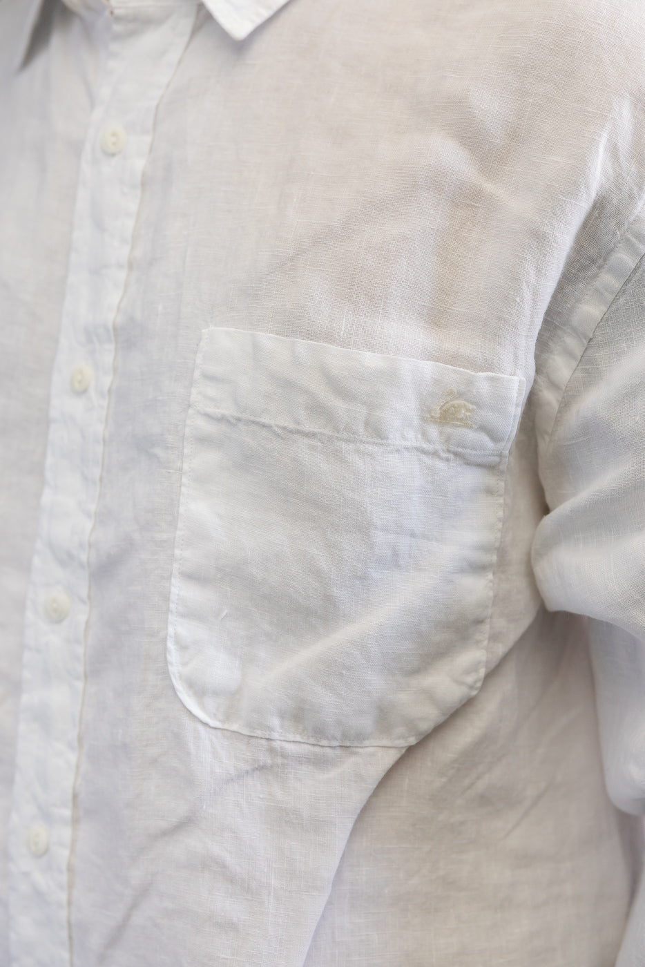 Close-up of front left chest pocket, buttons, and collar on white organic linen long sleeve shirt.