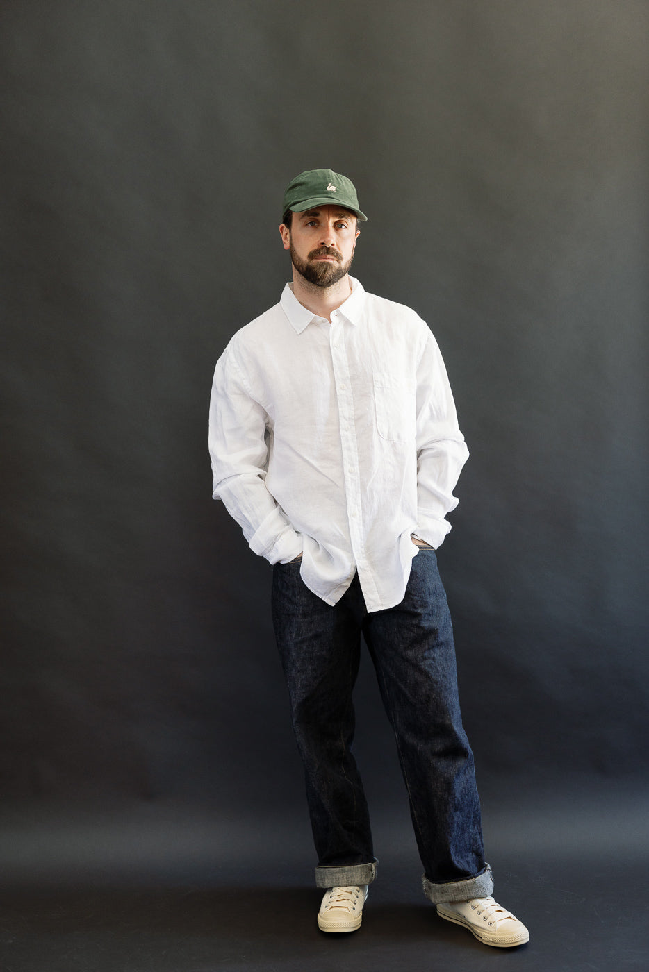 Full body front view of male model 5'9 165lbs athletic build wearing white organic linen long sleeve shirt with button front and chest pocket
