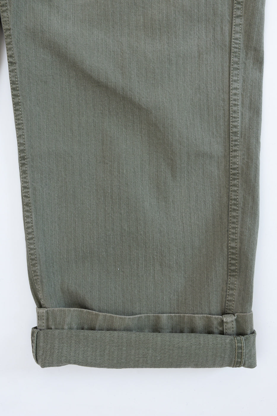 Close-up of the bottom hem of olive green pants, showing the folded cuff and fabric texture.