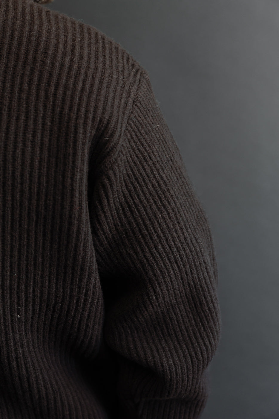 Close-up side view of a brown ribbed fabric texture on a garment sleeve and shoulder.