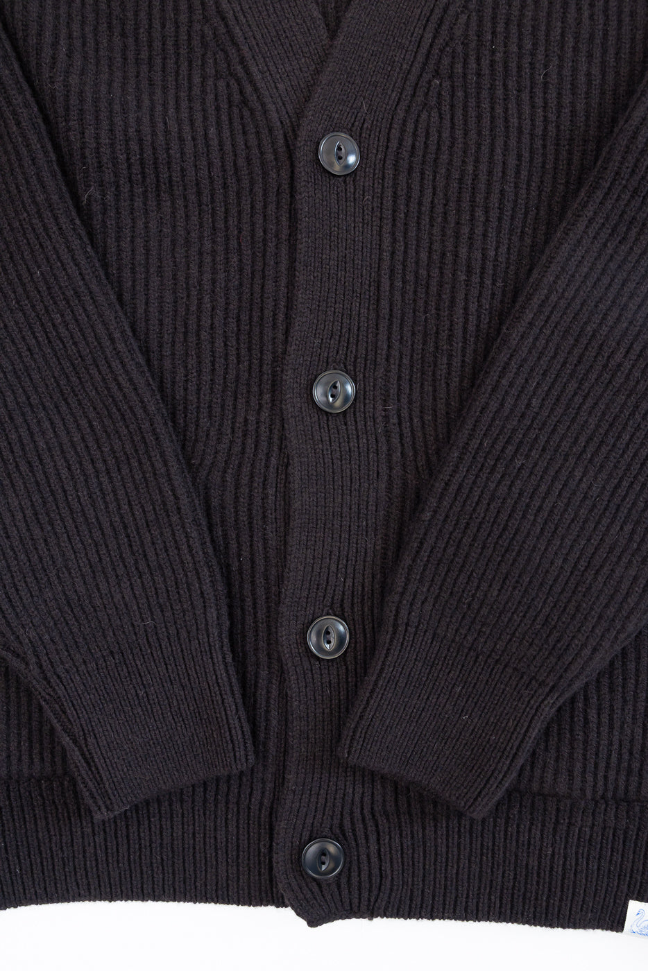 Close-up front view of black ribbed knit cardigan showing button details and fabric texture.