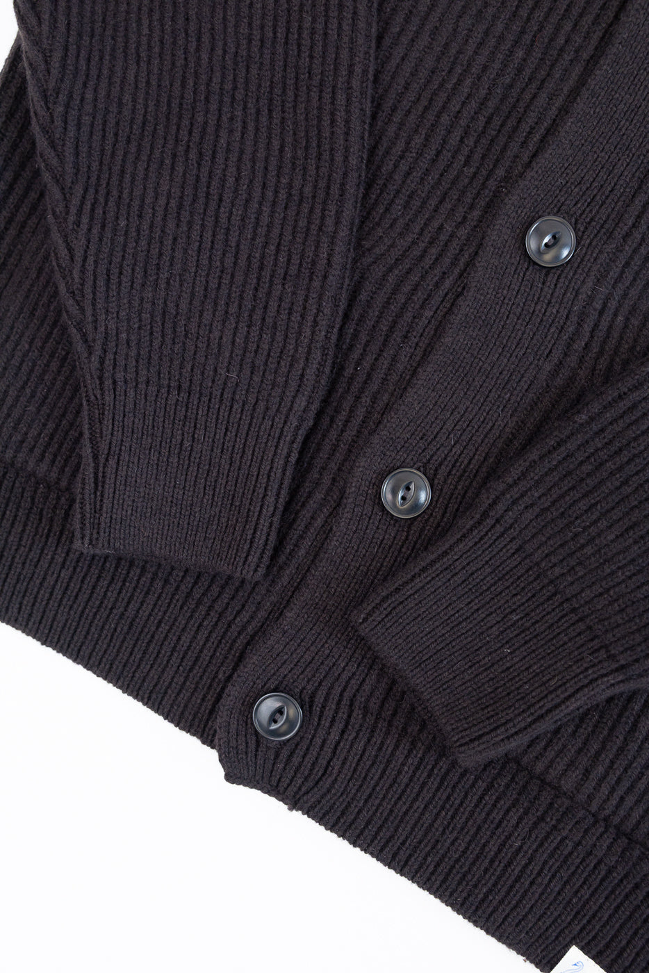 Close-up front view of dark brown ribbed knit cardigan showing button details and fabric texture.