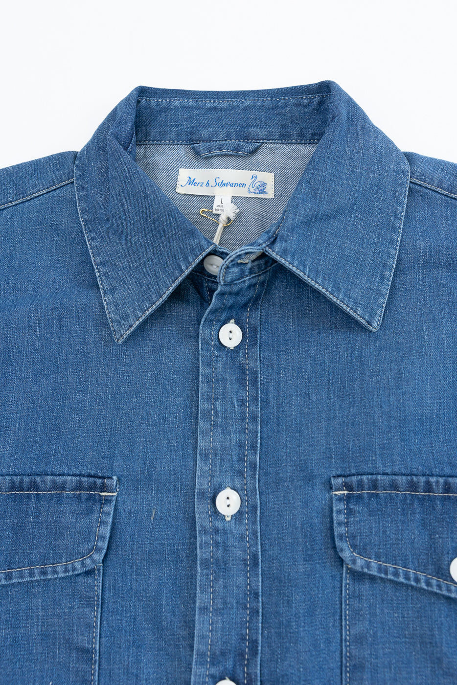 Close-up front view of a blue denim shirt showing the collar, button placket, and fabric texture.