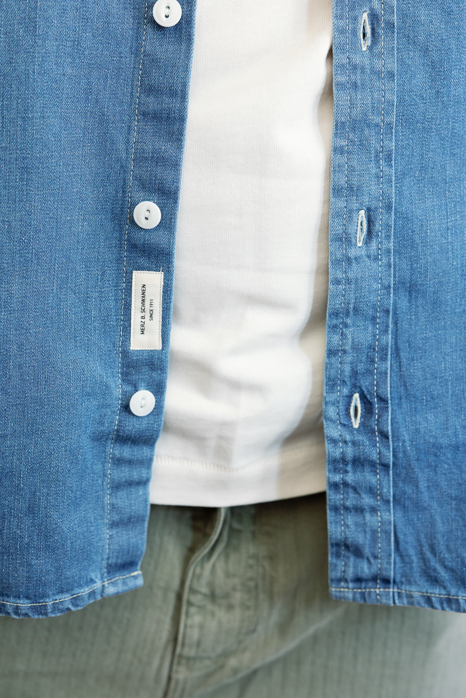 Close-up front view of a blue denim shirt showing white buttons and fabric texture.