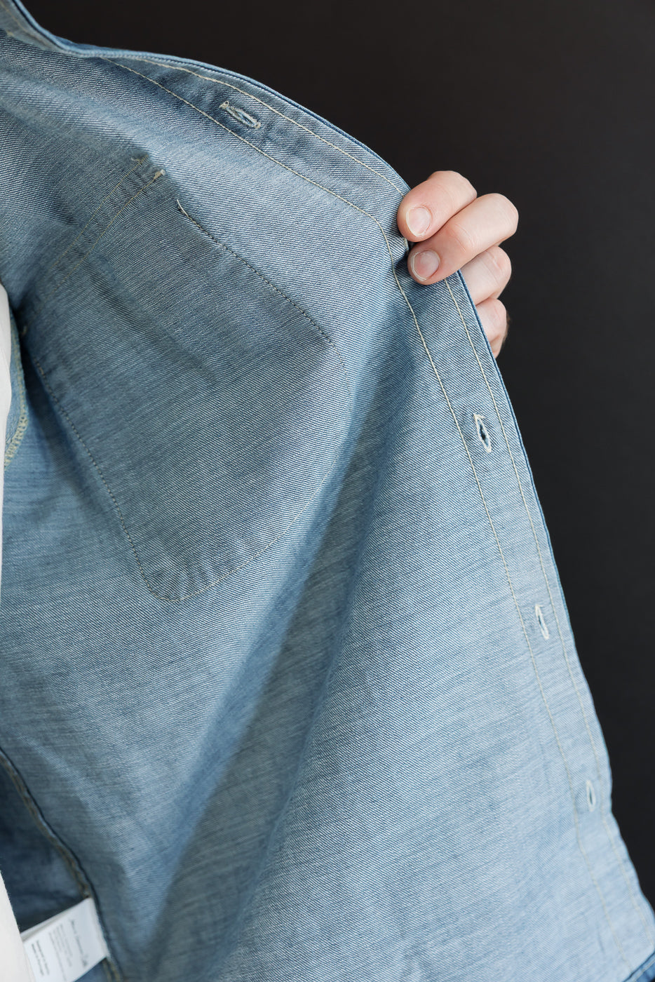 Close-up of the inner front right of a light blue denim shirt on a 5'9
