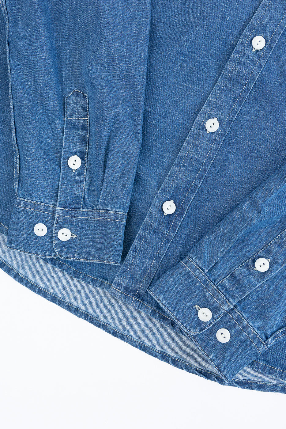 Close-up front view of blue denim shirt showing cuff details, buttons, and fabric texture.