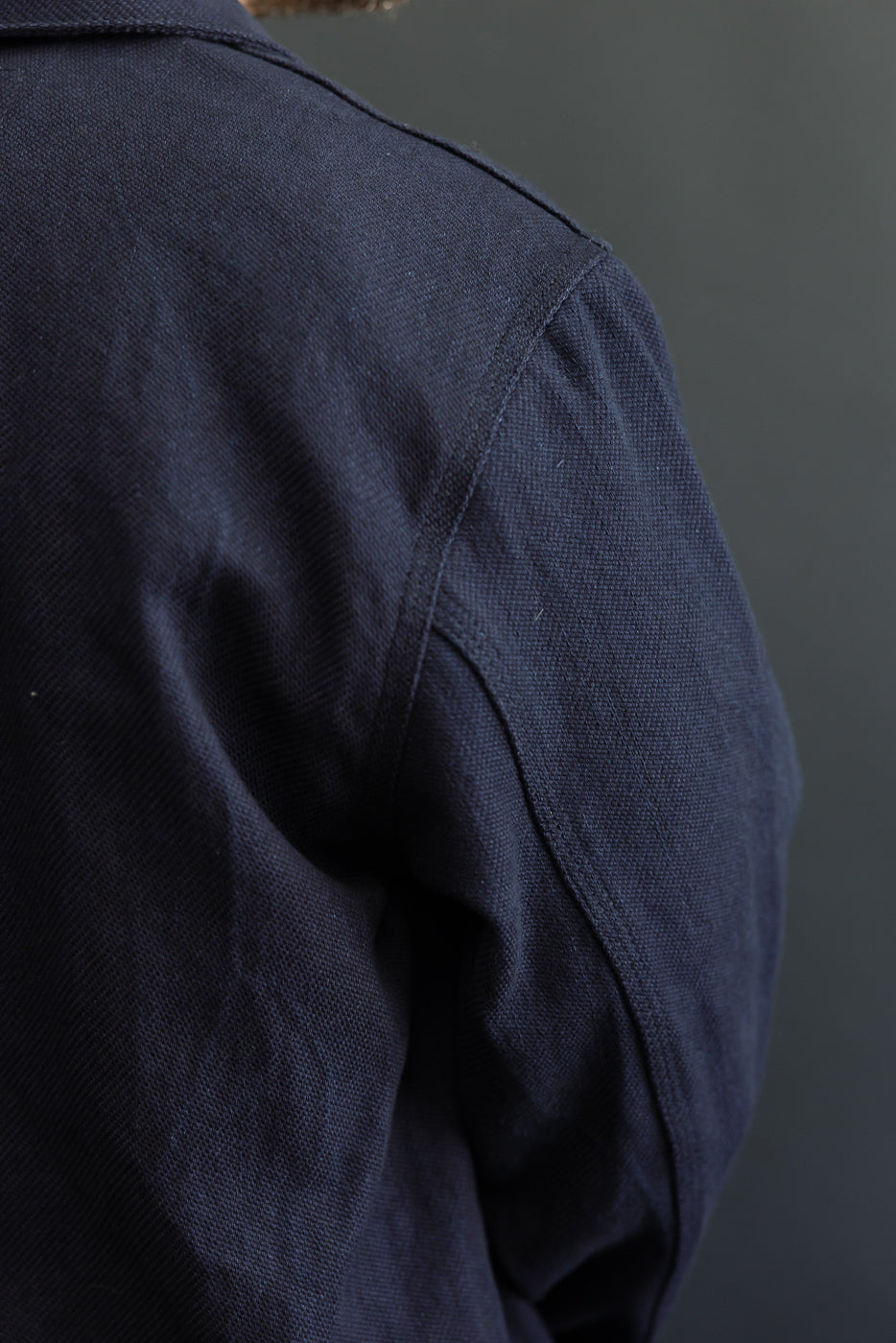 Close-up back shoulder view of navy work shirt on male model, 5'9