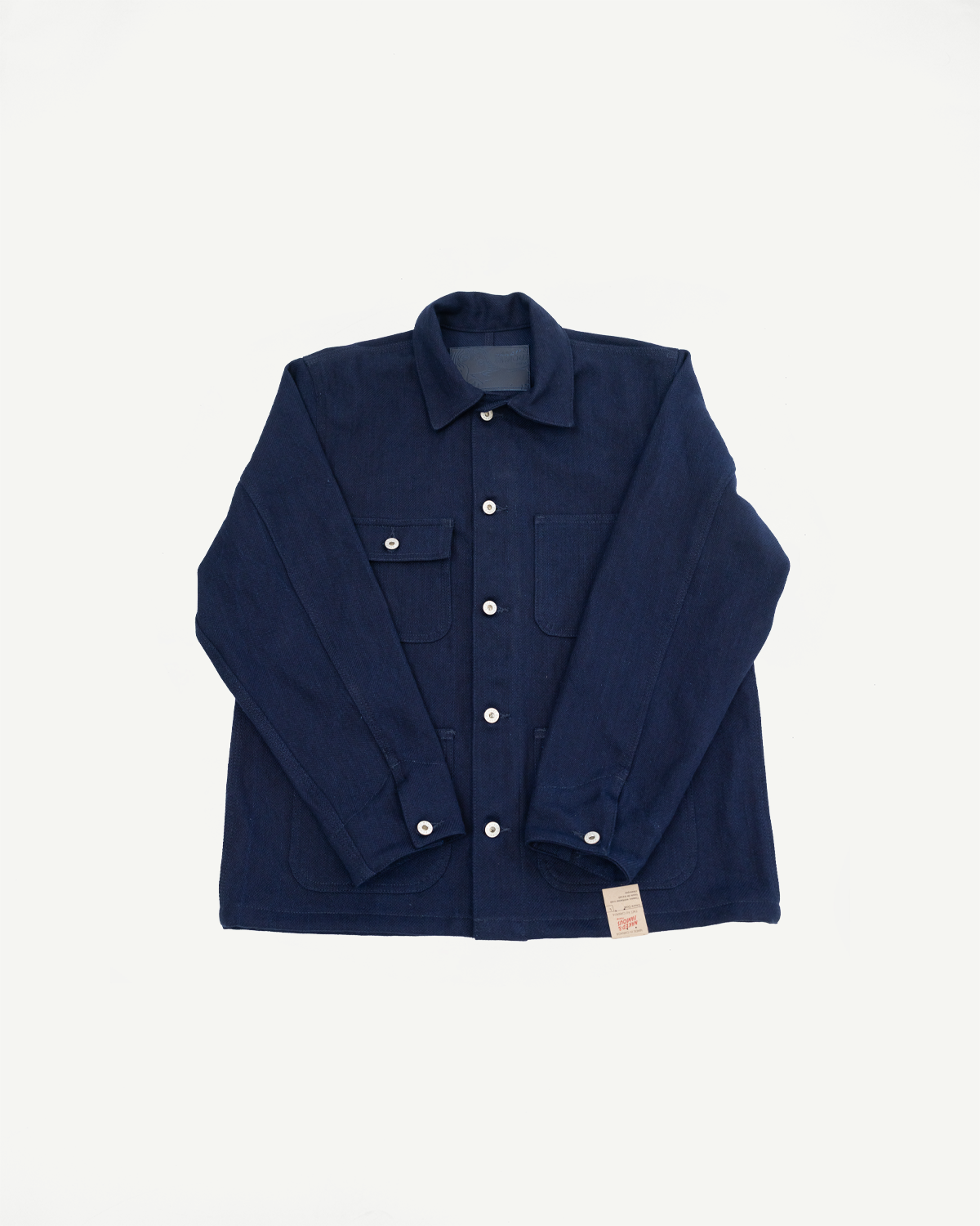 Flat lay front view of navy work shirt with button cuffs, chest pockets, and selvedge tag detail