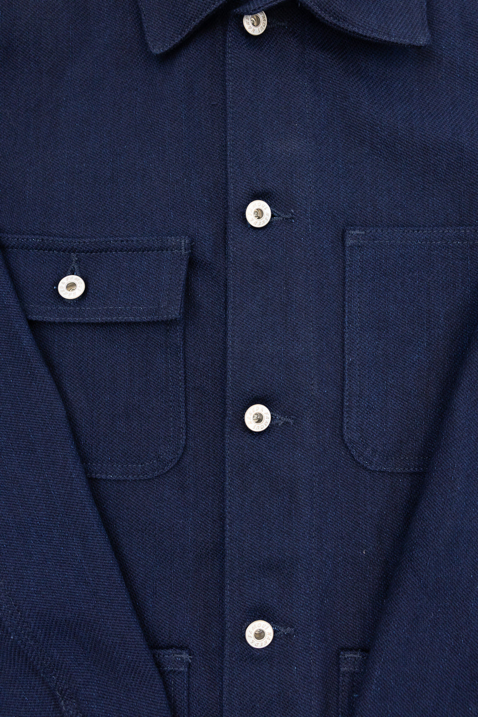 Close-up front view of navy work shirt: button placket, chest pockets, silver buttons, textured fabric