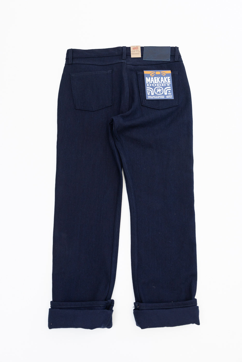 Back view of dark selvedge jeans with cuffed hems and branded patch on rear pocket