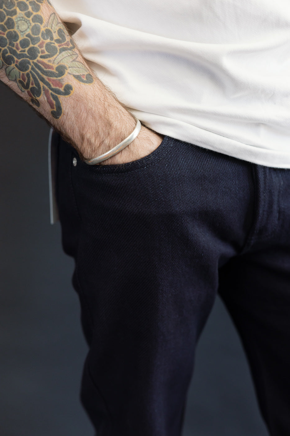 Close-up of male model's side, showcasing dark selvedge jeans with visible texture and white tee.