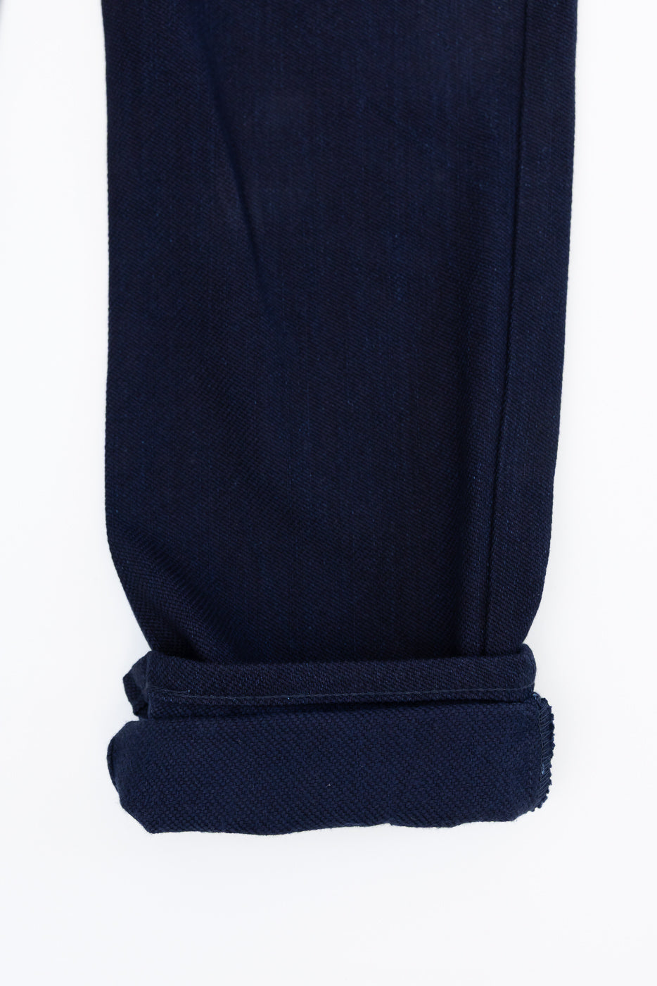 Close-up of dark blue selvedge jeans hem, showcasing rolled cuff and fabric texture