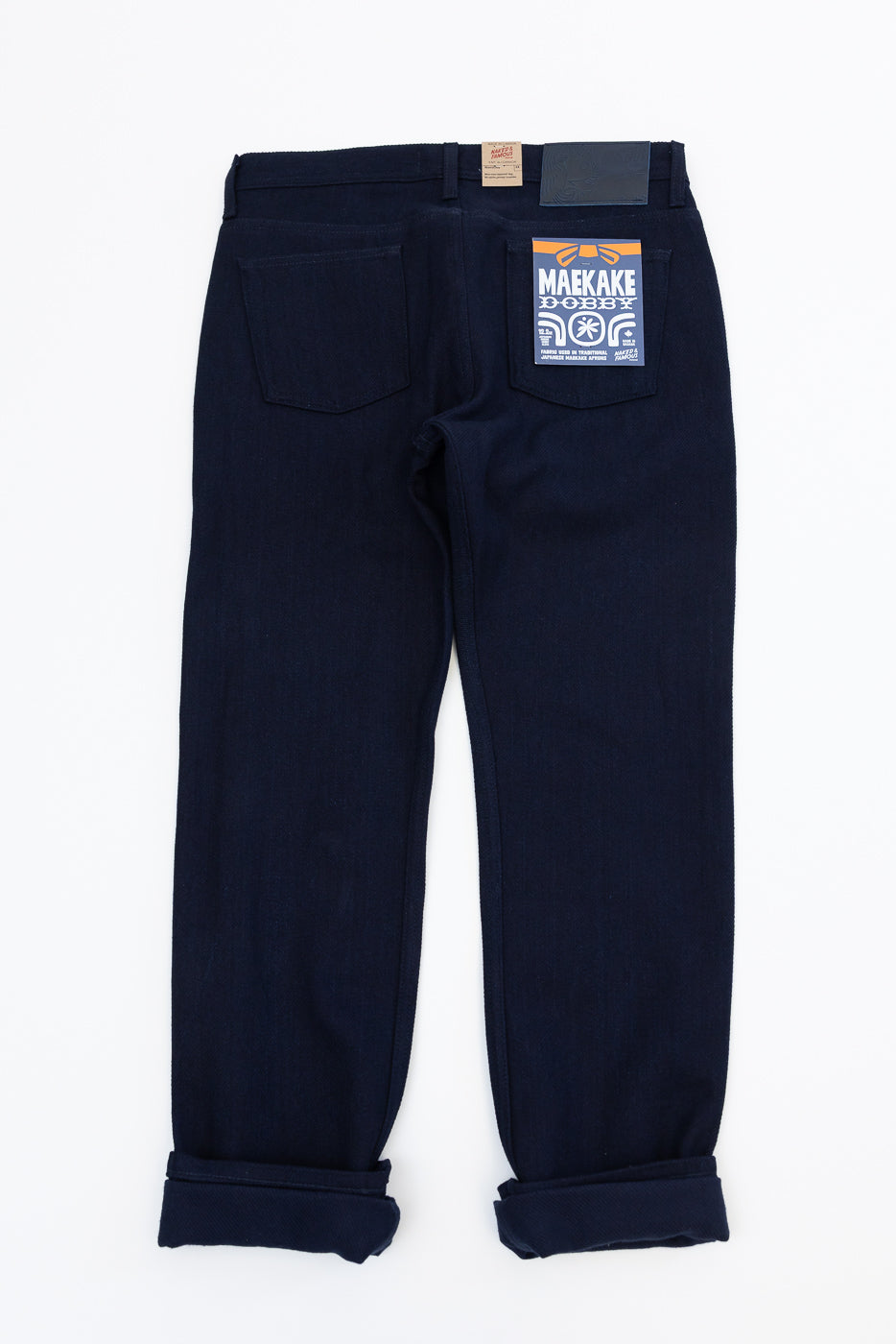 Back view of dark selvedge jeans with rolled cuffs, tag details, and rear pockets visible