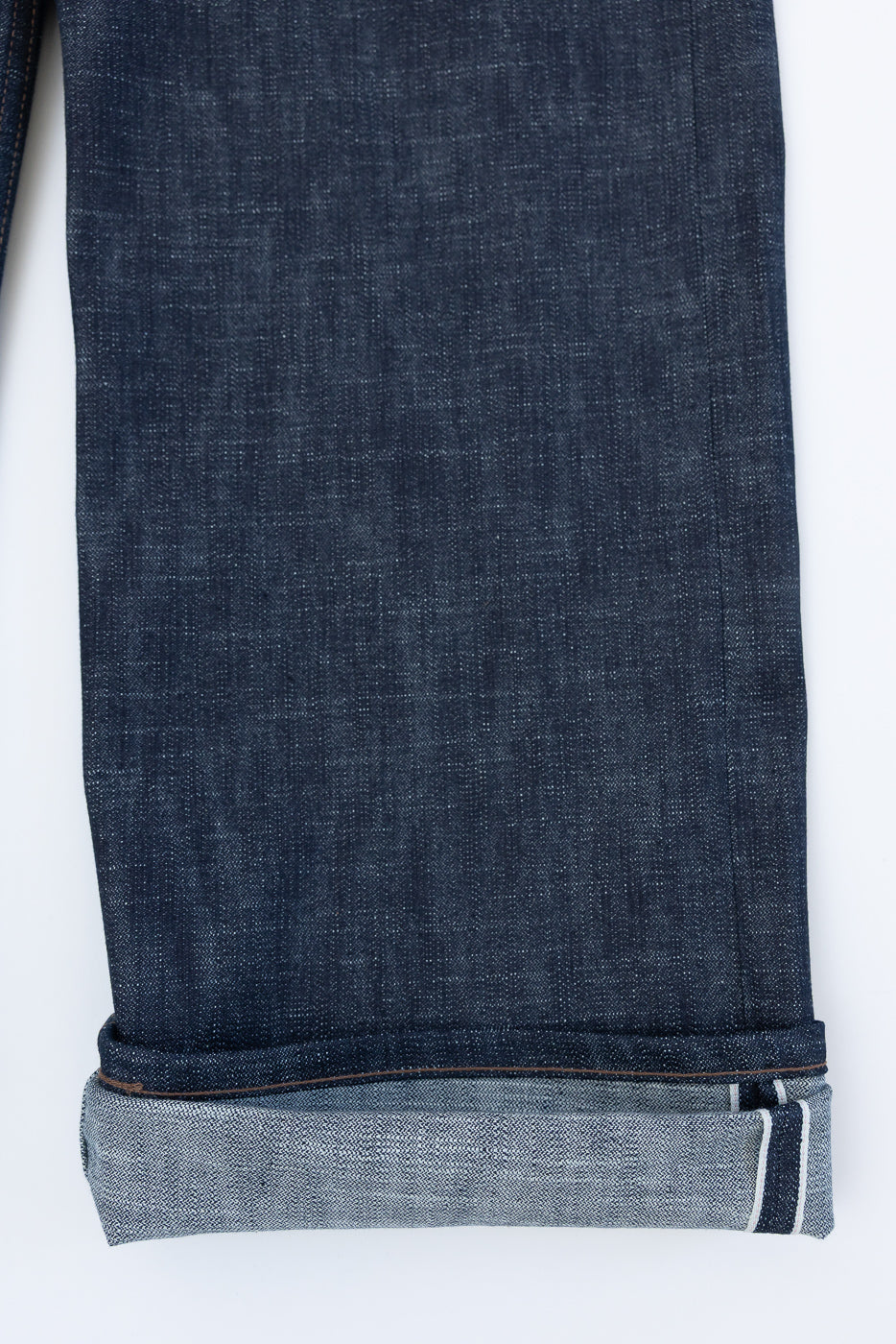 Cuffed hem of 12.5oz Greencast Stretch Selvedge jeans, highlighting the white-pink-white selvedge edge, showcasing the unique slub texture and green-cast indigo of Naked & Famous's premium denim.