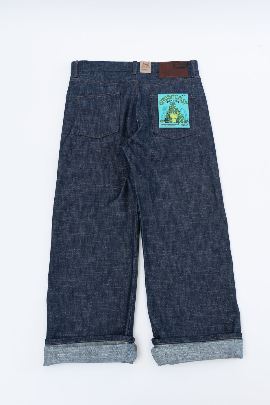 Back view of 12.5oz Greencast Stretch Selvedge - Strong Guy jeans featuring wide-leg design, rolled cuffs revealing selvedge, two back patch pockets, and a leather brand patch.