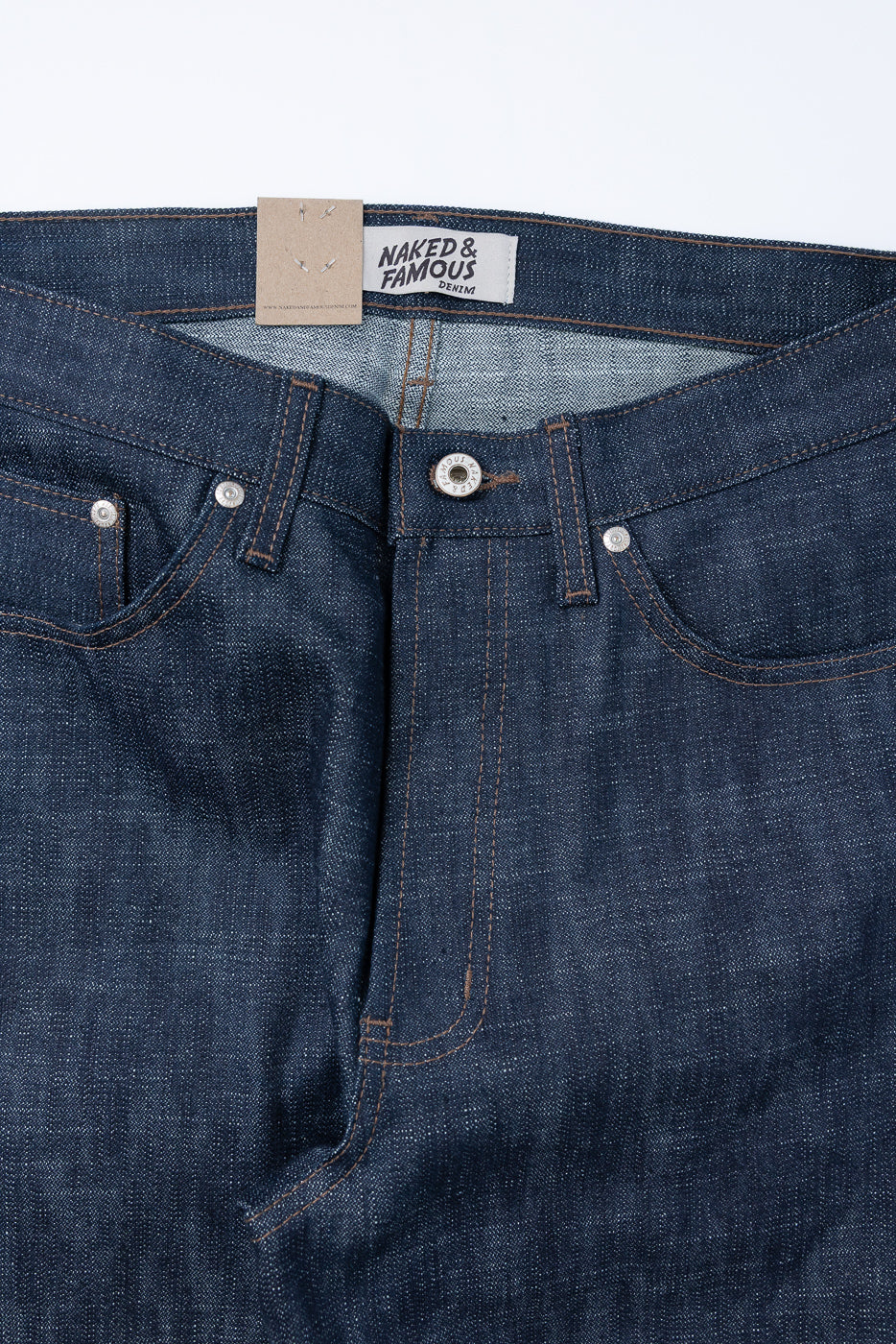 12.5oz Greencast Stretch Selvedge - True Guy jeans featuring a dark-indigo waistband with belt loops, visible metal button fly, rust top-stitching, and a Naked & Famous Denim label inside the waistband.