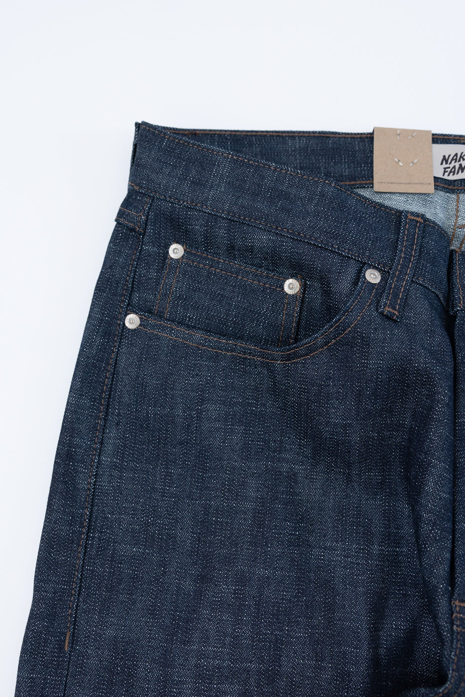 12.5oz - Greencast Stretch Selvedge - True Guy: Upper front view of raw indigo denim jeans, showcasing waistband, belt loop, front pocket, coin pocket, and metal rivets. Selvedge denim with subtle green cast for dynamic fading.