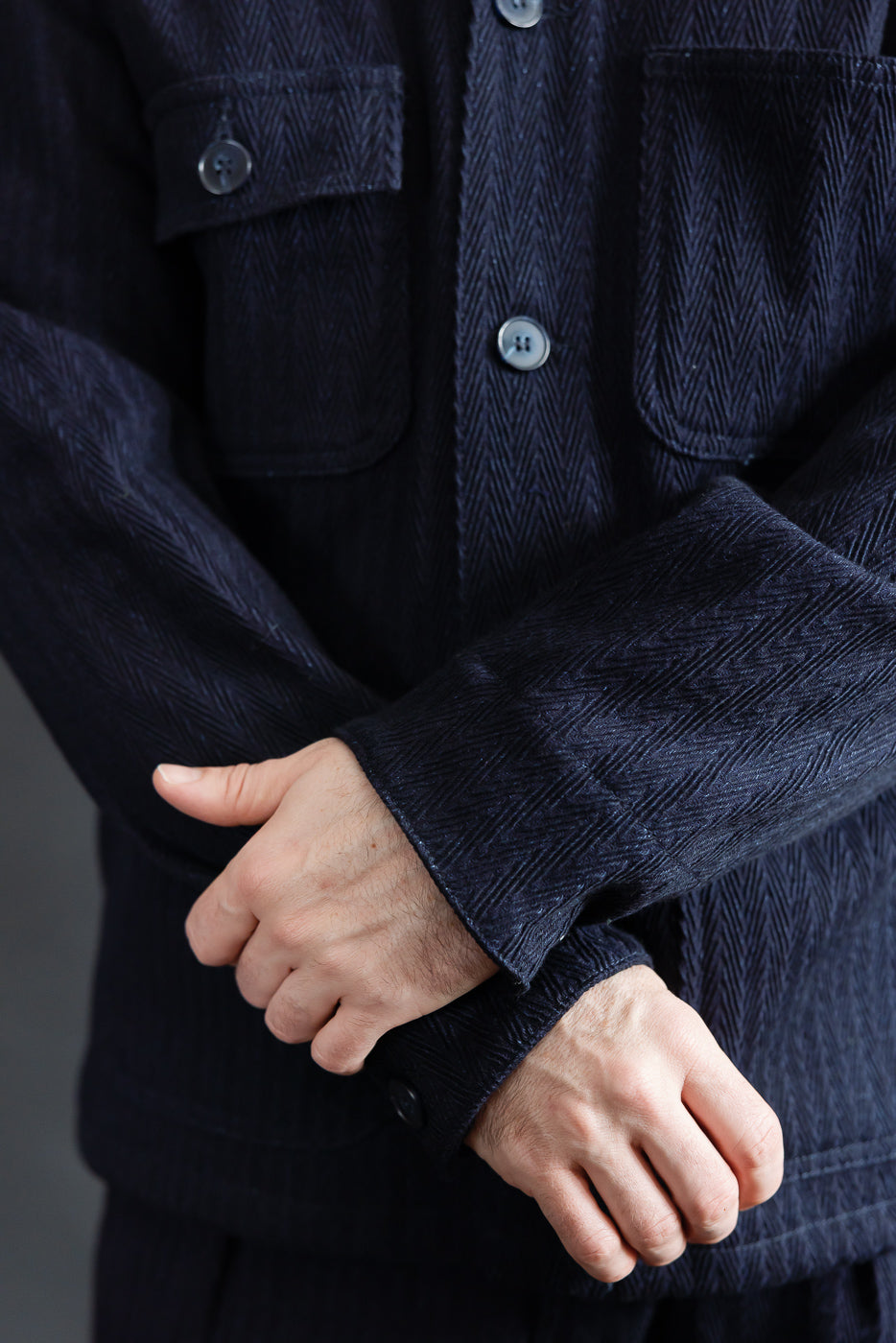 Close-up front of Naked & Famous 12oz indigo chore coat, herringbone fabric, chest pockets, male model 5'9