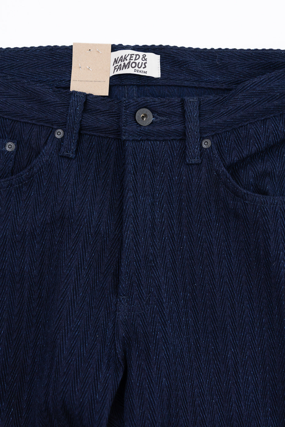 Close-up front view of Naked & Famous indigo selvedge jeans, button, waistband, herringbone texture.