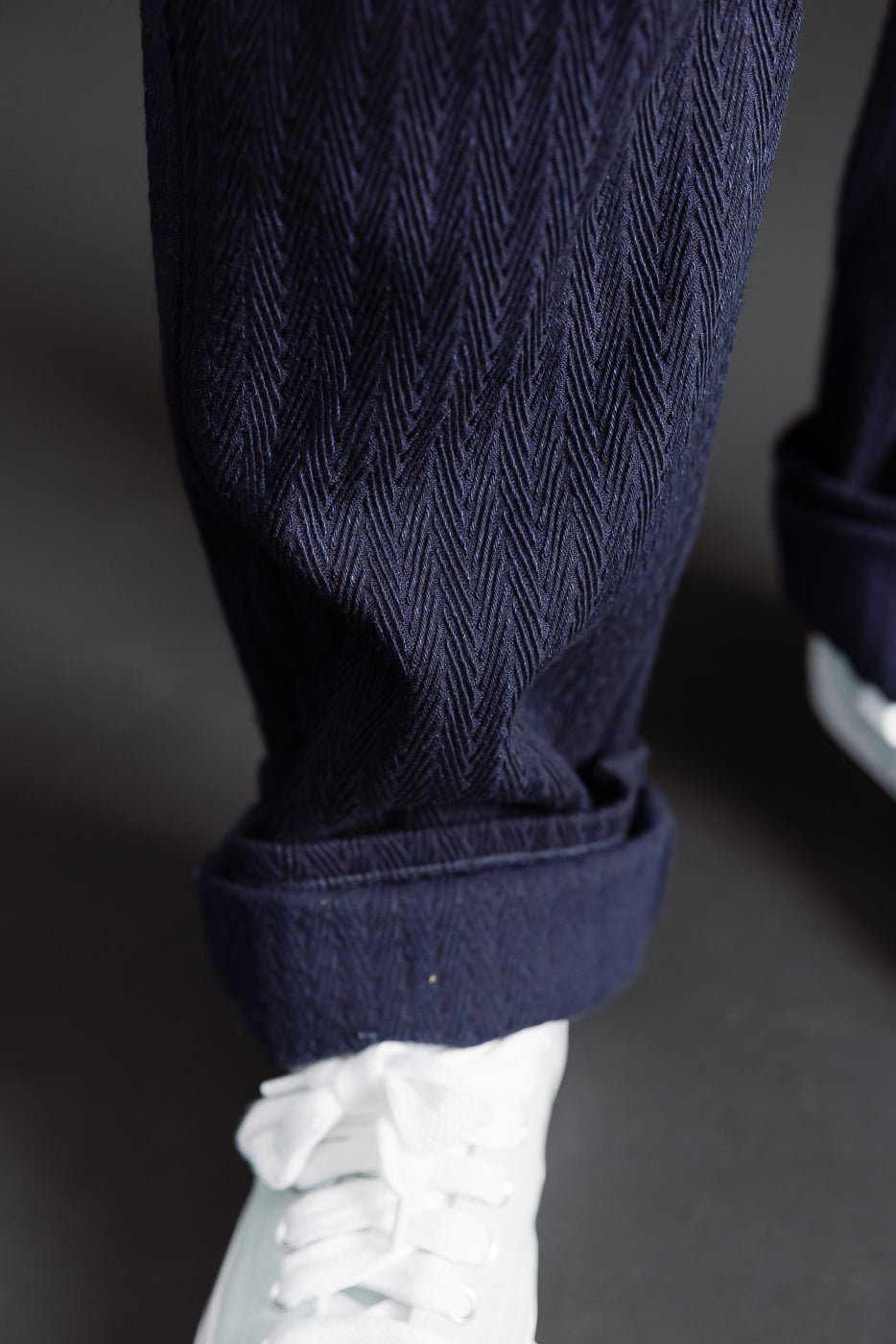 Close-up of selvedge denim texture and cuff on front left leg, worn by male model, Dant