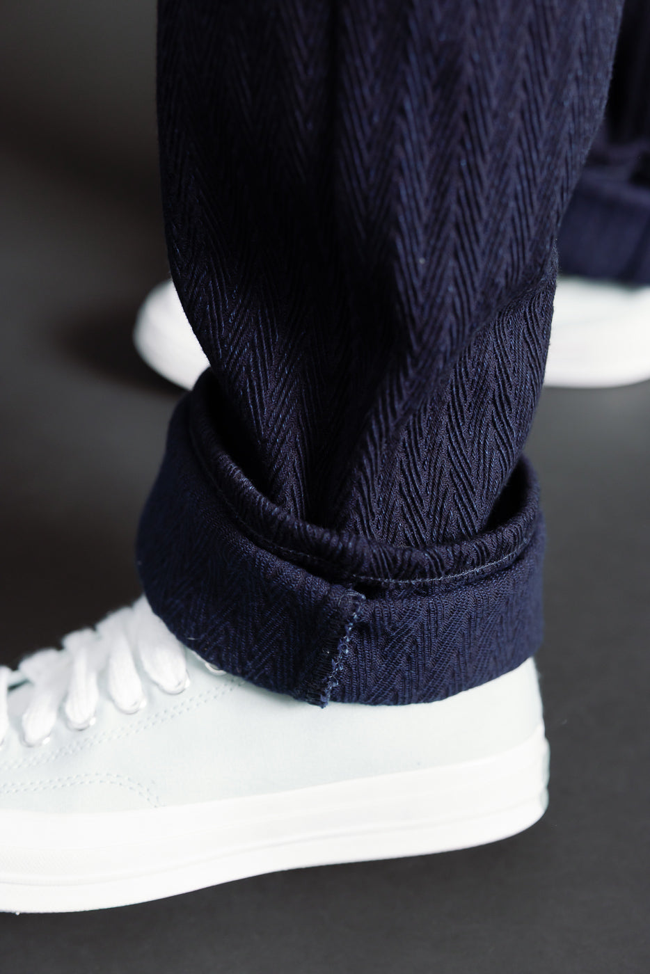 Close-up of cuffed Naked & Famous 12oz indigo selvedge jeans hem texture on male model, side view.