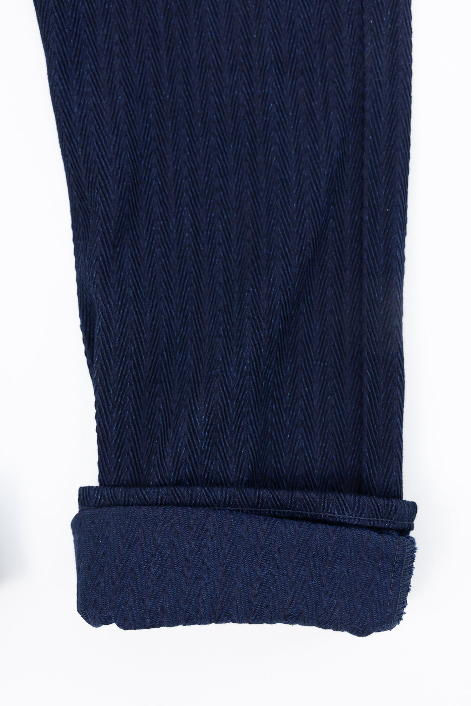 Close-up of Naked & Famous 12oz indigo selvedge jeans cuff, showing herringbone texture, pant leg hem detail, front view.