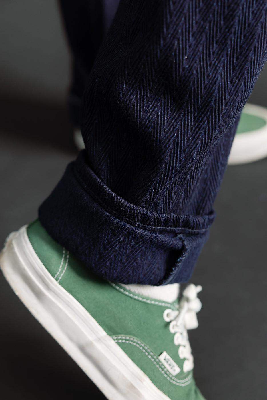 Close-up of male model pant cuff, herringbone selvedge denim, lower leg, side view.