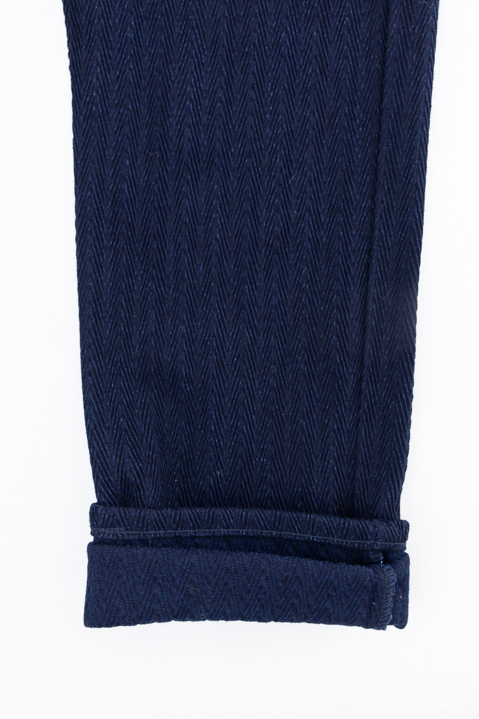 Close-up of Naked & Famous 12oz indigo selvedge jeans hem, leg front, showing herringbone denim texture and cuff details