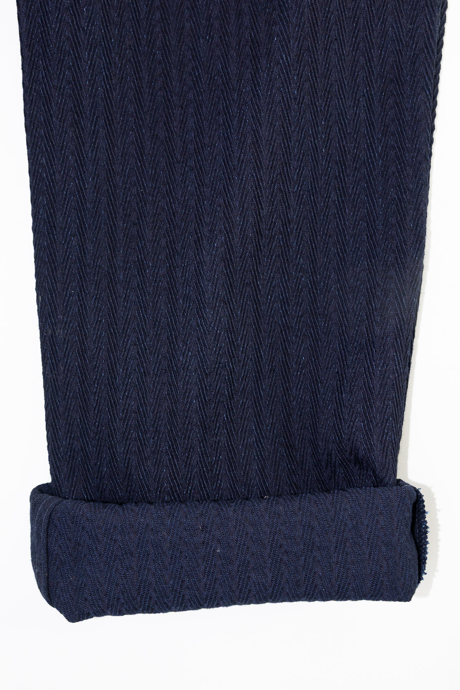 Close-up of front hem and cuff of Naked & Famous 12oz indigo pleated trouser, herringbone texture