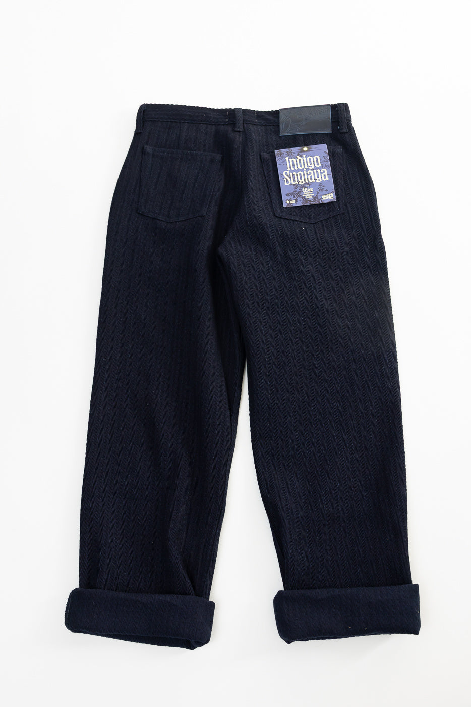 Flat lay back view of Naked & Famous 12oz Indigo Sugiaya pleated trousers, back pockets visible