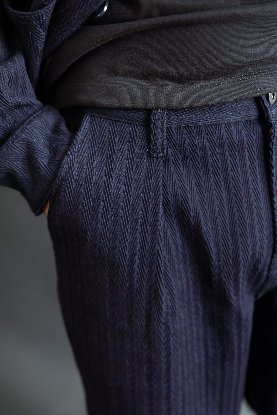 Close-up front view of Naked & Famous indigo pleated trouser on male model, 5'9
