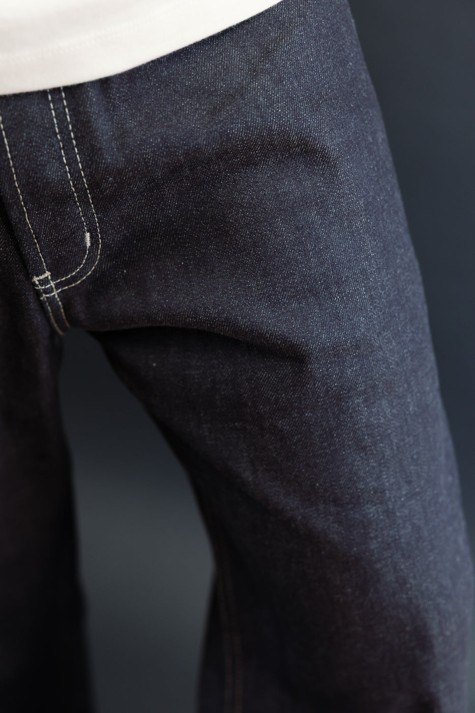 Close-up of front left hip of dark indigo selvedge denim jeans on male model, 5'9