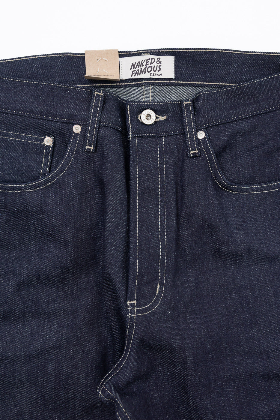 Close-up front view of Naked & Famous Denim jeans showing waistband, button, and fabric texture.