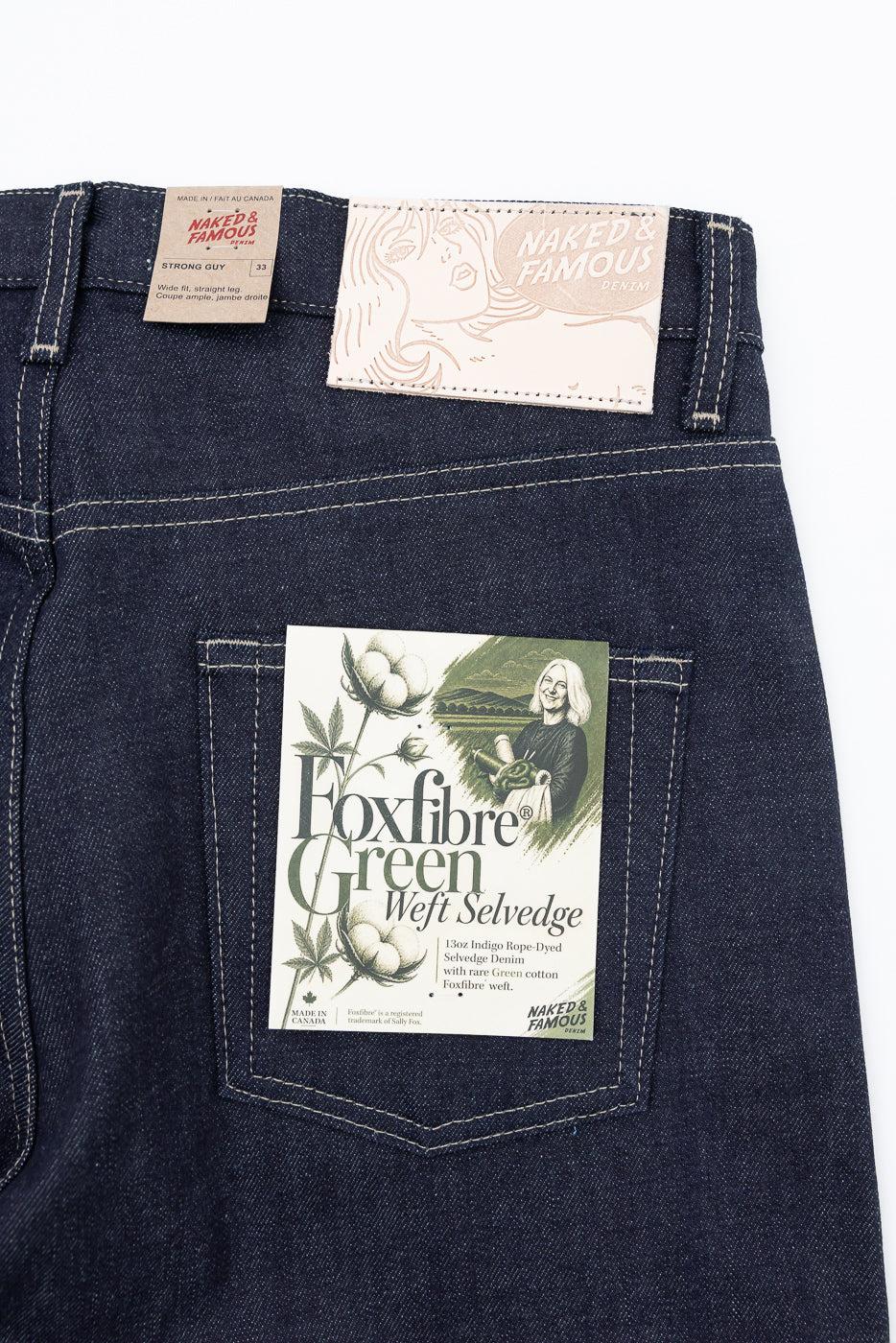 Close-up of back waist and pocket of Naked & Famous denim with product tags.