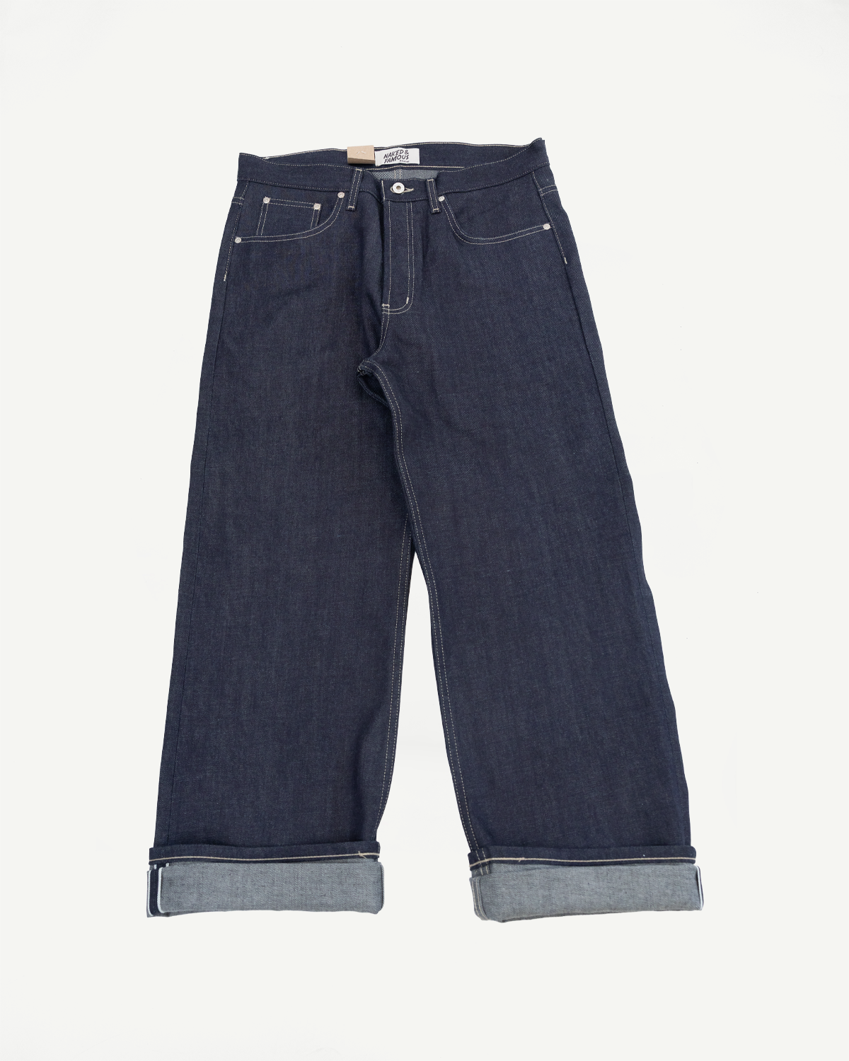 Front view flat lay of dark indigo selvedge denim jeans with cuffed hems.