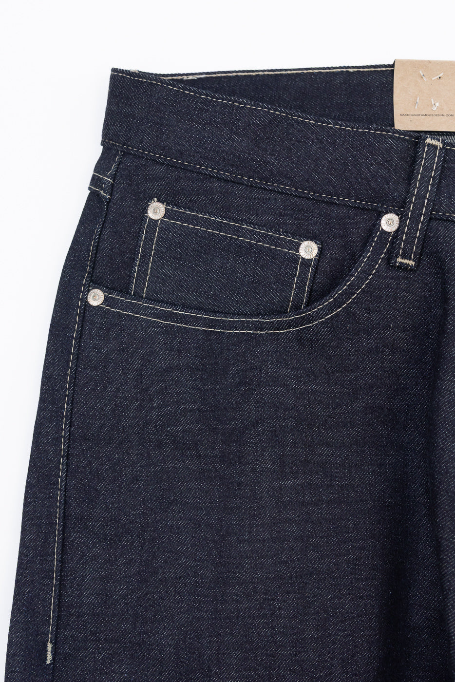 Close-up front view of dark indigo denim jeans showing pocket stitching and metal rivets.