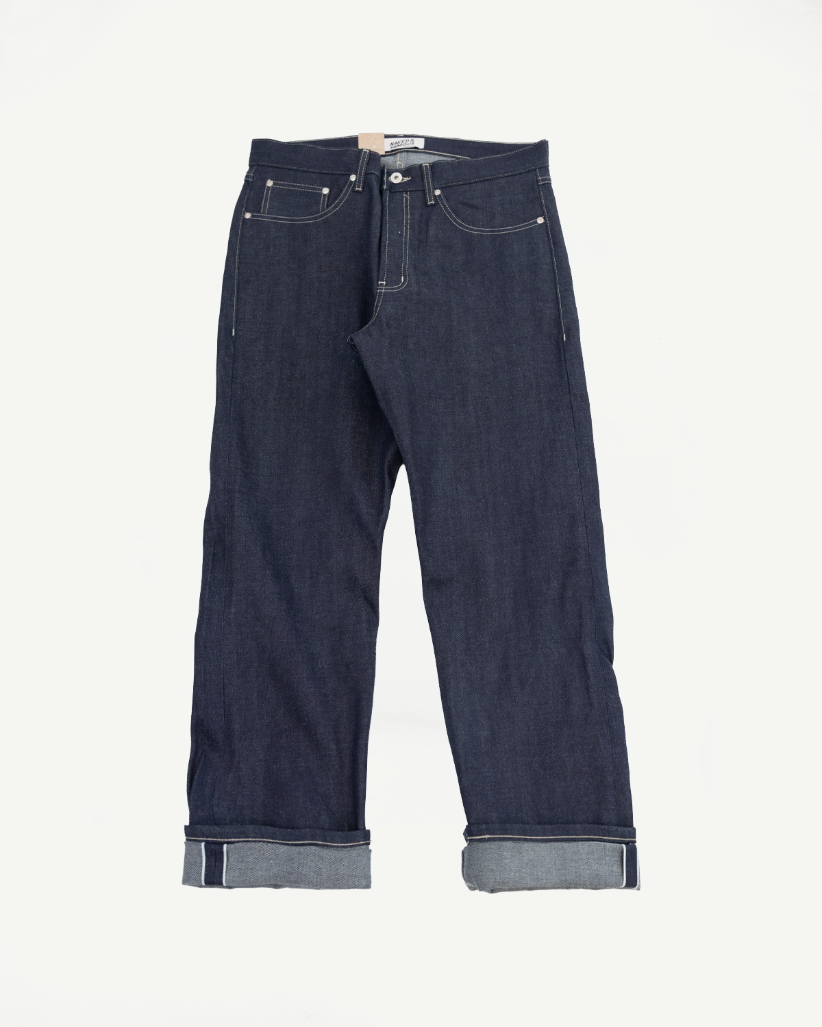 Front view flat lay of dark indigo selvedge denim jeans with cuffed hems on white background.