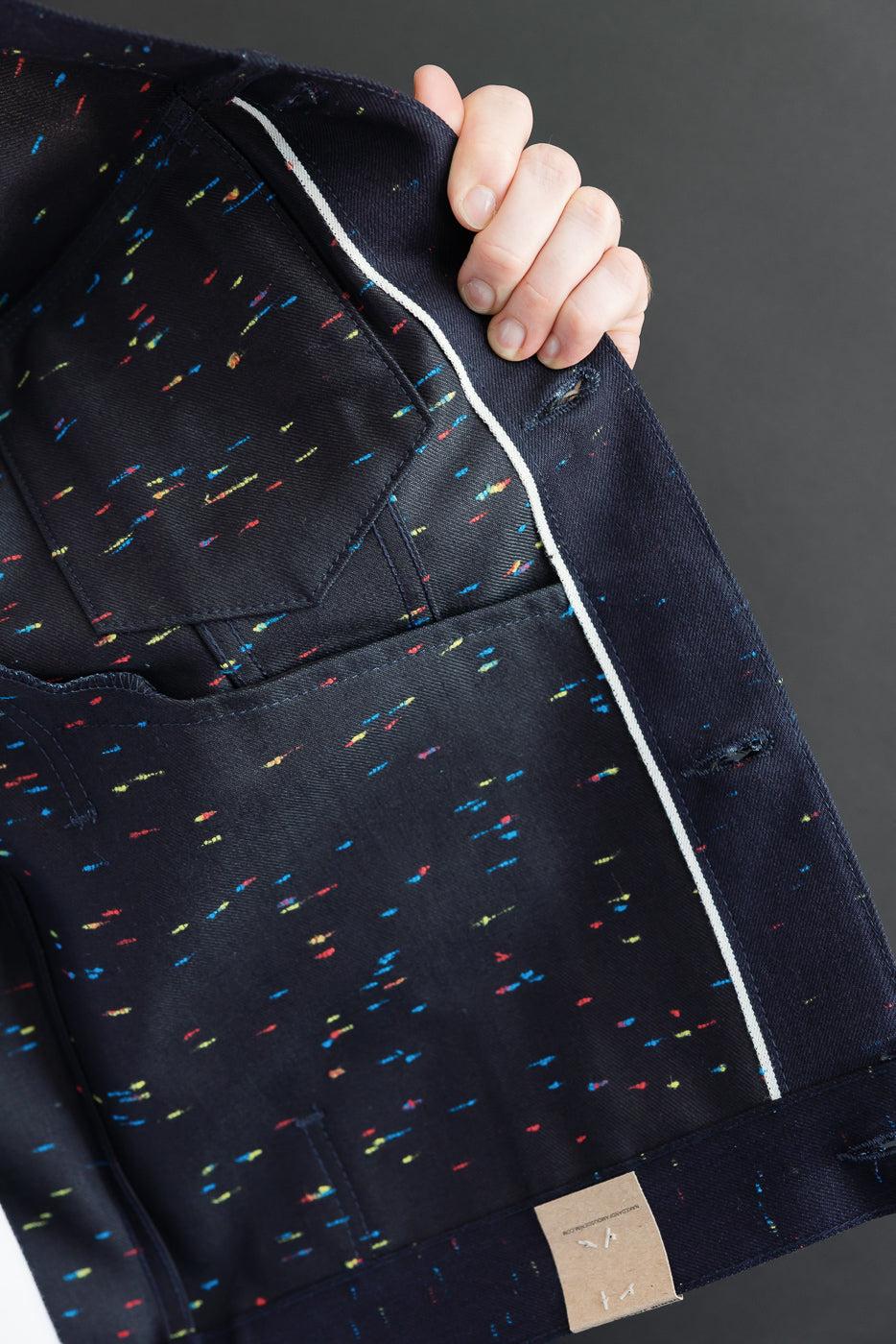 Close-up of the interior lining of a navy garment featuring a colorful confetti pattern.