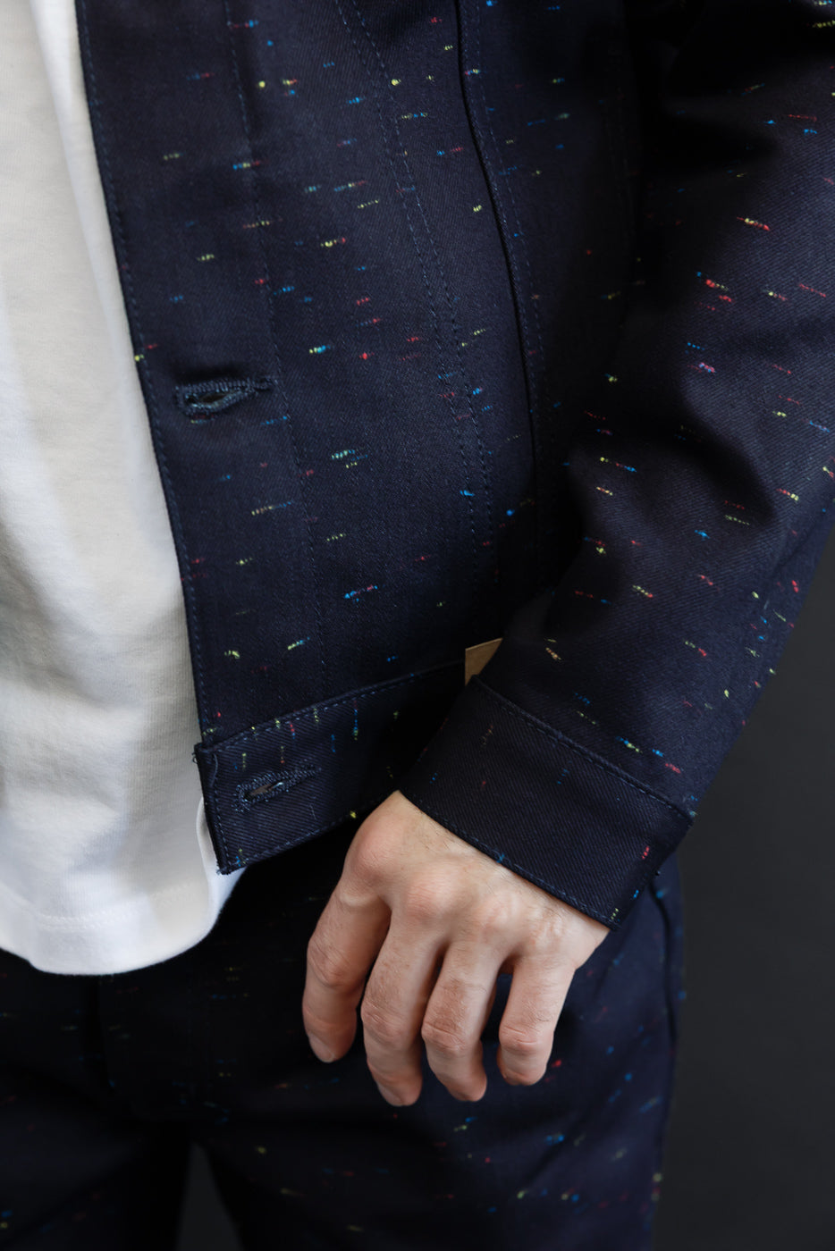 Close-up of the front left side of a male model's navy patterned denim jacket showing sleeve and cuff.