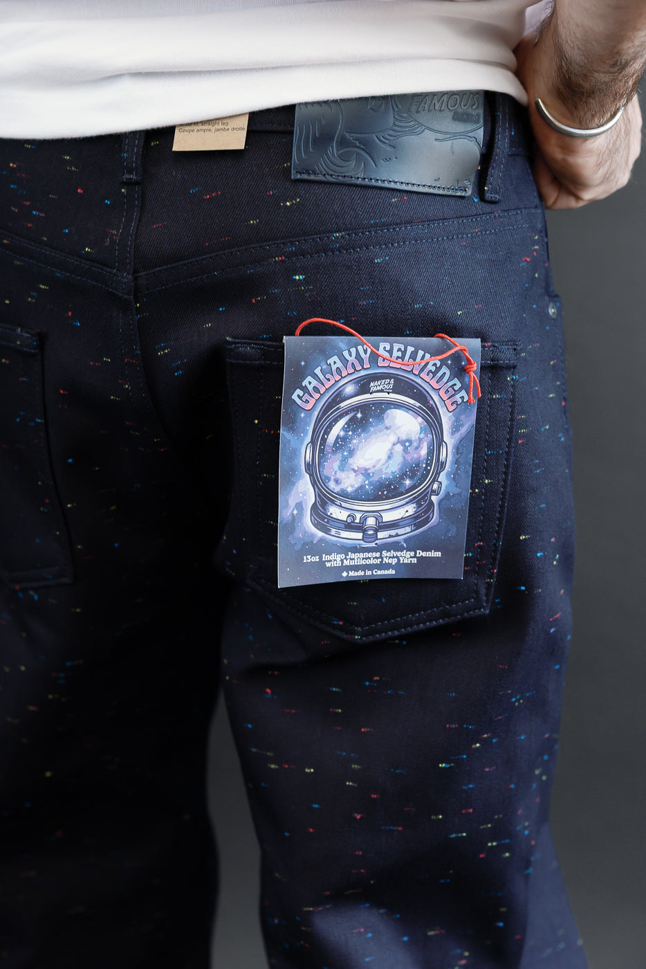 Close-up back view of dark indigo selvedge denim jeans with colorful nep yarn speckles and a galaxy tag.