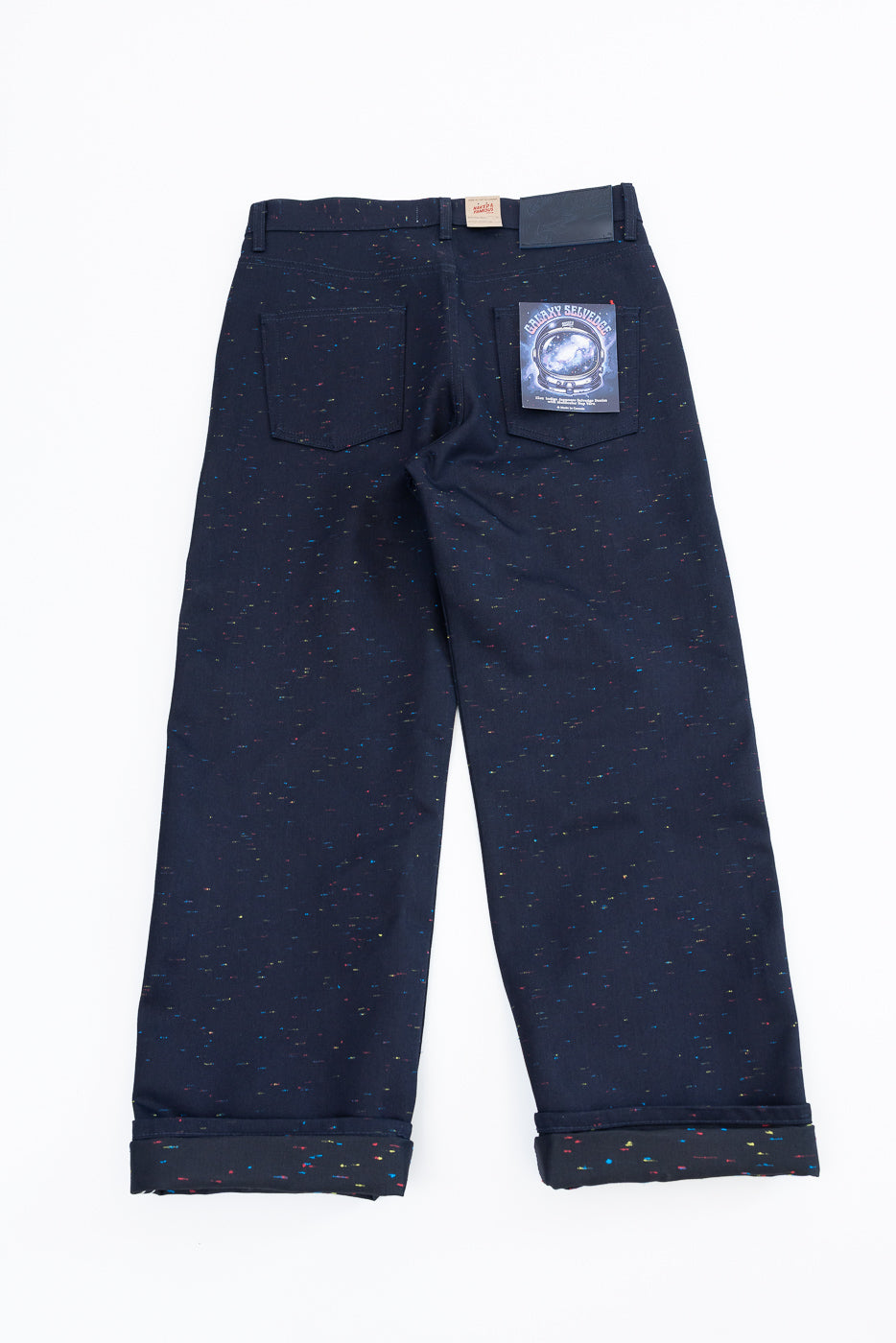Back view flat lay of navy speckled selvedge denim pants showing rear pockets and brand patch.