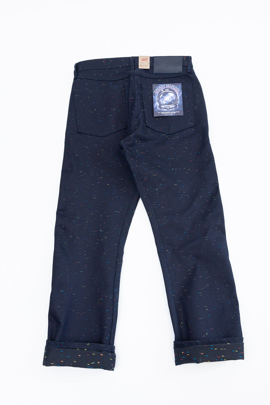 Back view flat lay of navy speckled selvedge denim jeans with a graphic leather patch.