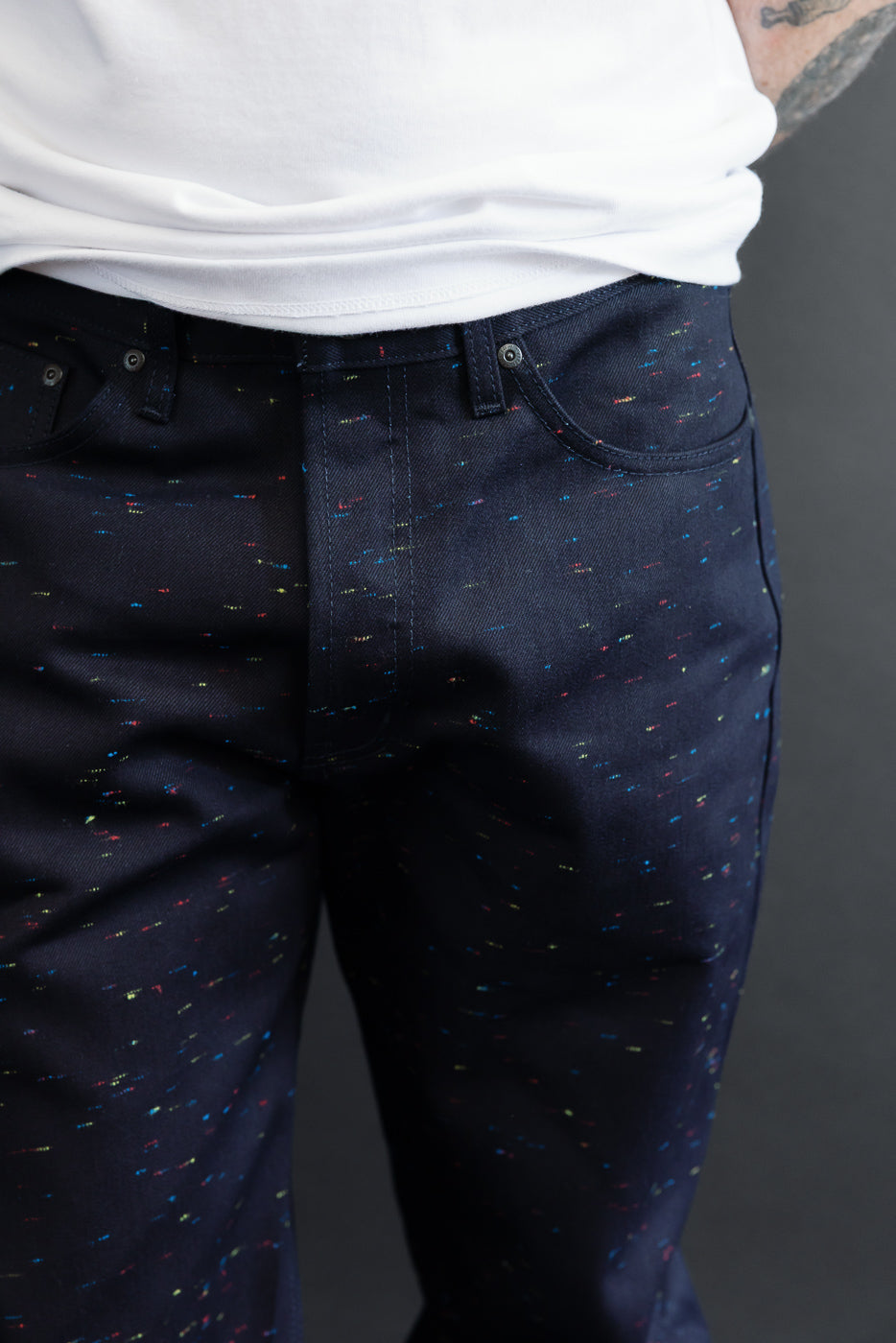 Close-up front view of dark indigo speckled denim trousers on a male model, 5'9