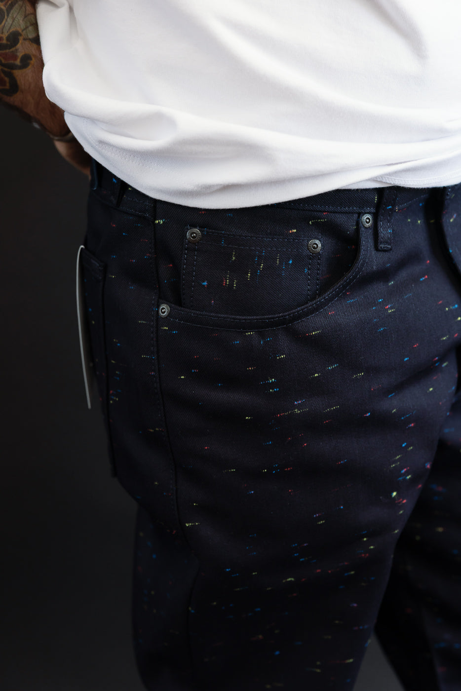 Close-up side view of the back pocket and hip of dark navy patterned trousers on a male model.